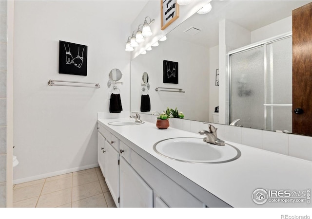 bathroom with a shower with door, vanity, and tile patterned floors