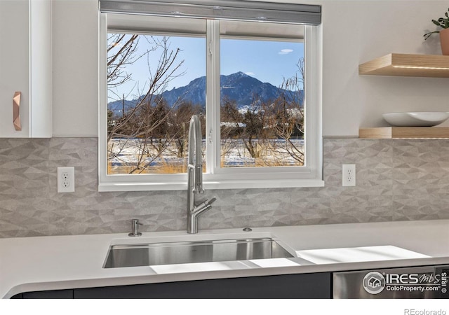 kitchen featuring backsplash, a mountain view, light countertops, and a sink