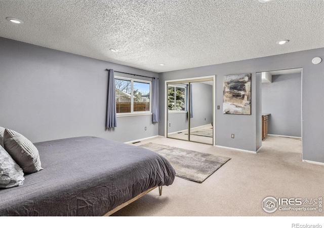 bedroom featuring light carpet, a textured ceiling, baseboards, and a closet