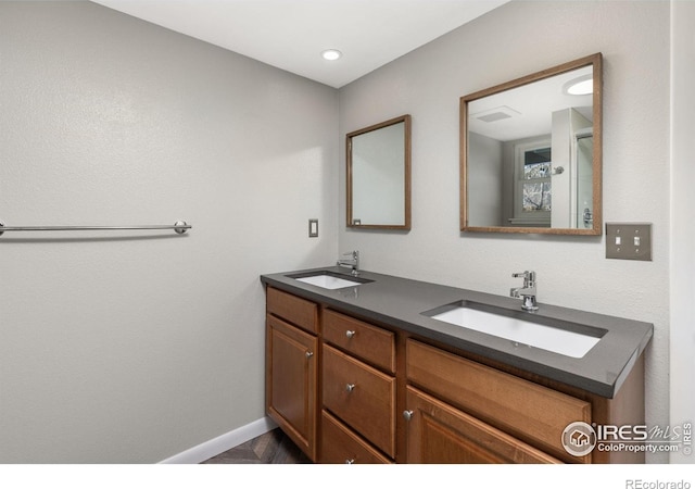 bathroom featuring a sink, baseboards, and double vanity