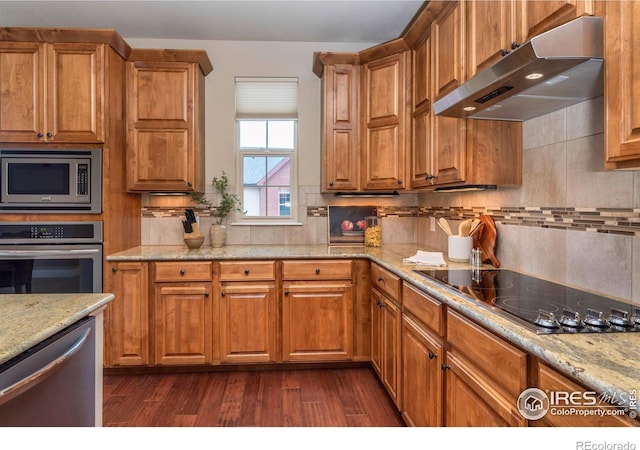 kitchen featuring light stone countertops, appliances with stainless steel finishes, dark hardwood / wood-style floors, and decorative backsplash