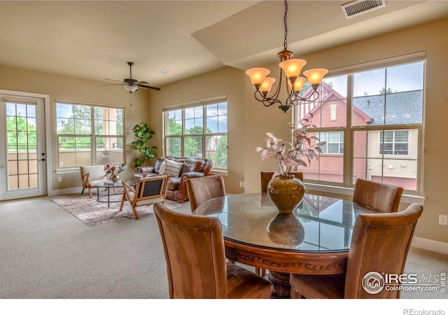 carpeted dining area featuring ceiling fan with notable chandelier