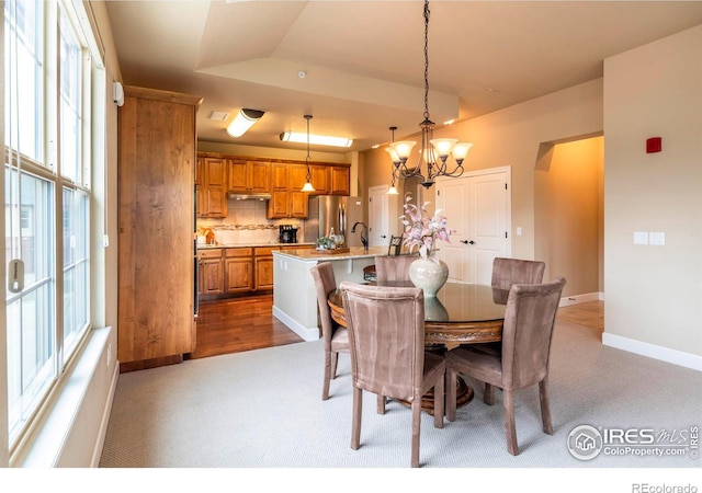 dining space with light colored carpet, lofted ceiling, and a chandelier