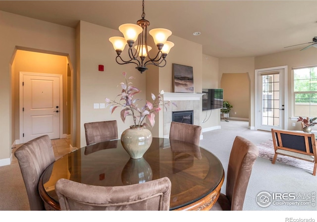 carpeted dining room featuring a tiled fireplace and a notable chandelier