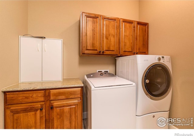 clothes washing area featuring cabinets and separate washer and dryer