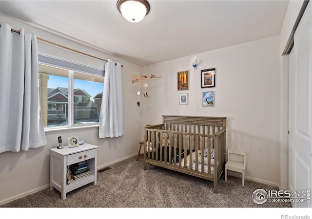 bedroom featuring a crib, carpet flooring, and a closet