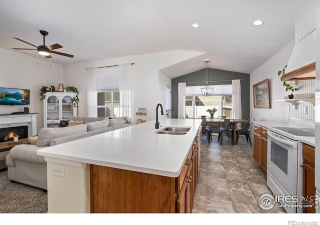 kitchen with sink, white electric range, an island with sink, a healthy amount of sunlight, and decorative light fixtures