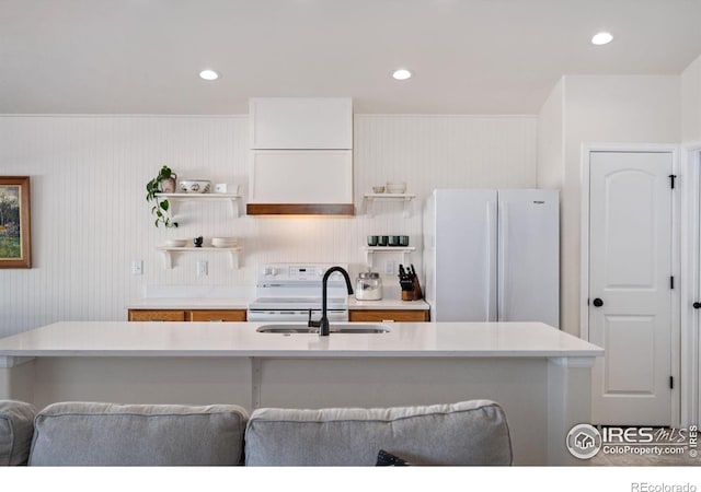 kitchen with sink, white appliances, a center island with sink, white cabinets, and a kitchen bar