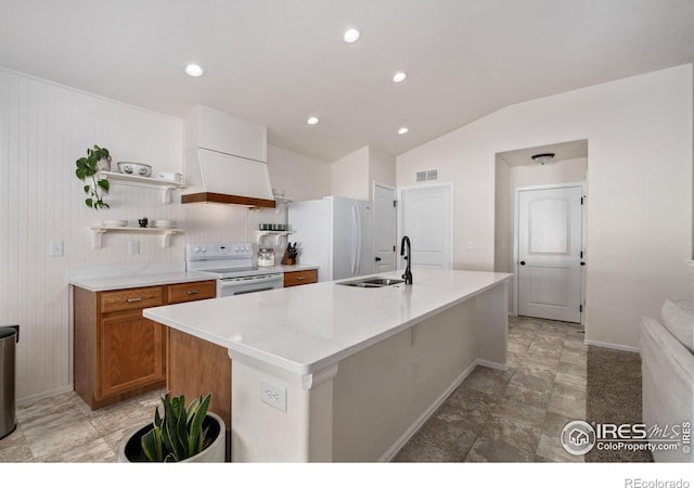 kitchen with lofted ceiling, sink, a center island with sink, and white appliances