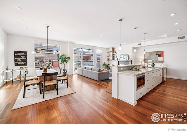 kitchen featuring pendant lighting, dishwasher, wood-type flooring, built in microwave, and a chandelier