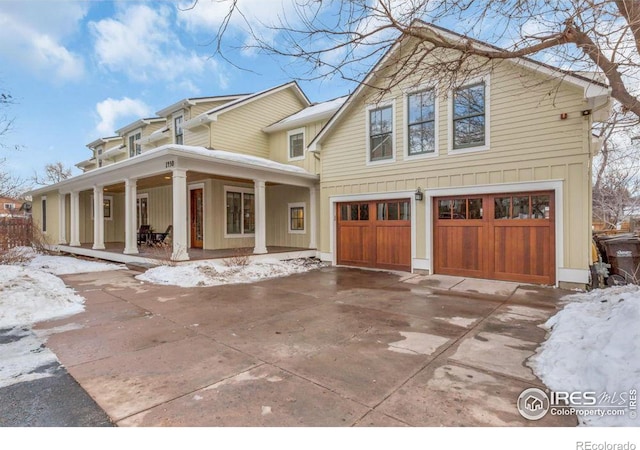 snow covered property with a garage and covered porch