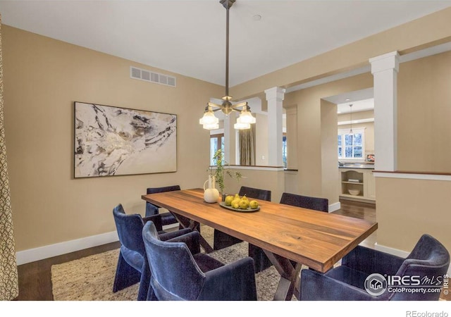 dining space featuring wood-type flooring and ornate columns