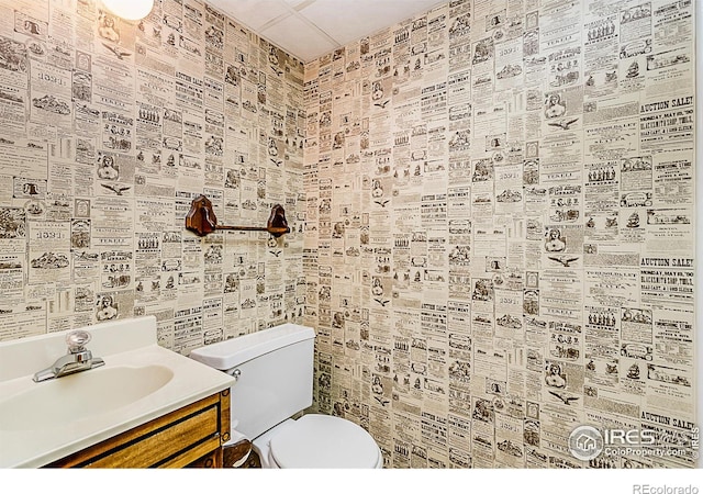 bathroom featuring vanity, toilet, and a drop ceiling