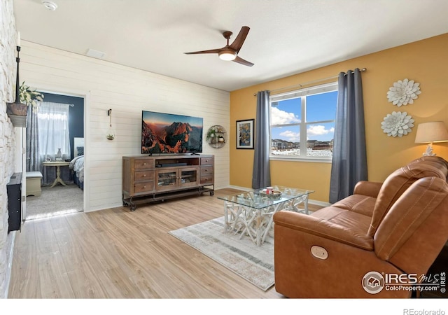 living room featuring hardwood / wood-style floors, ceiling fan, and wood walls