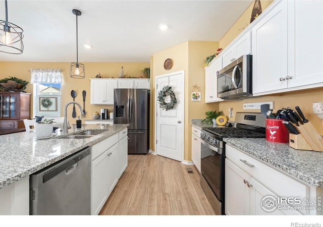 kitchen featuring stainless steel appliances, white cabinetry, hanging light fixtures, and sink