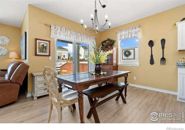 dining space featuring a notable chandelier, plenty of natural light, and light wood-type flooring