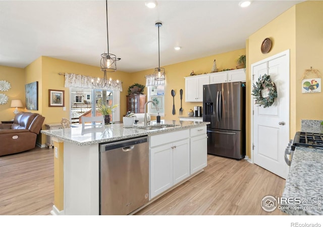 kitchen featuring white cabinetry, an island with sink, sink, hanging light fixtures, and stainless steel appliances