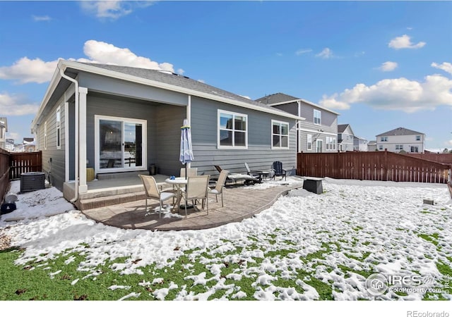 snow covered back of property featuring a patio