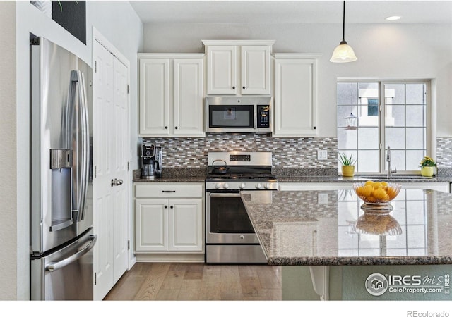 kitchen featuring sink, stainless steel appliances, dark stone counters, and white cabinets