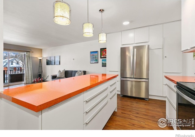 kitchen with hardwood / wood-style flooring, appliances with stainless steel finishes, pendant lighting, and white cabinets