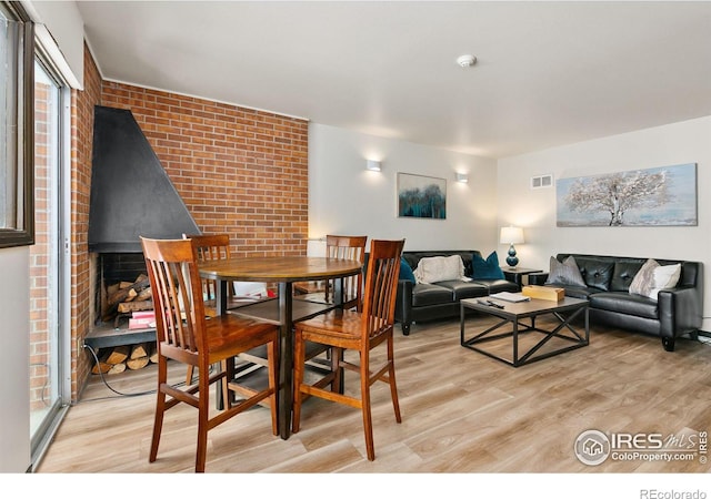 dining room featuring light hardwood / wood-style flooring and brick wall