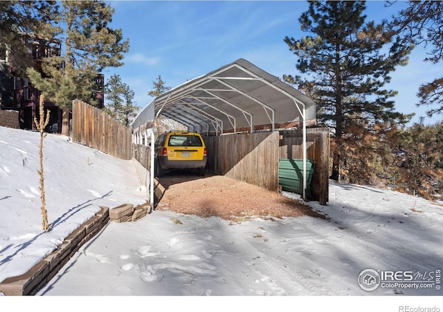 snow covered parking featuring a carport