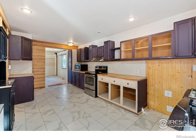 kitchen featuring dark brown cabinets, wooden walls, and appliances with stainless steel finishes