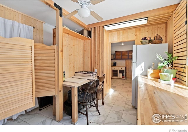 interior space featuring ceiling fan and wooden walls