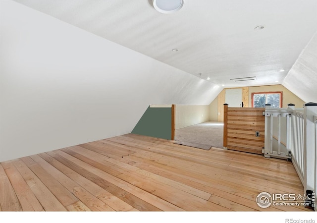 unfurnished bedroom featuring vaulted ceiling and light hardwood / wood-style floors