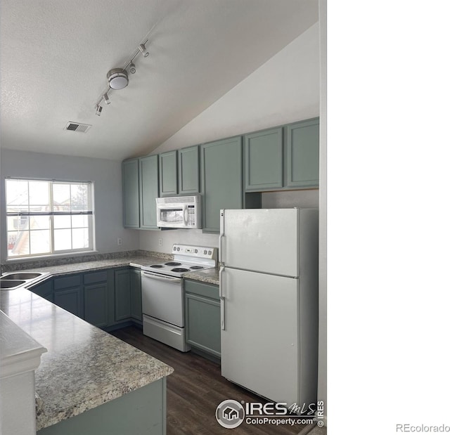 kitchen with white appliances, dark wood-type flooring, track lighting, a textured ceiling, and vaulted ceiling