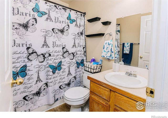 bathroom with vanity, tile patterned flooring, curtained shower, and toilet