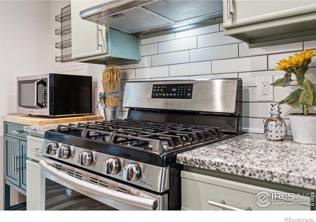 kitchen featuring tasteful backsplash, appliances with stainless steel finishes, light stone countertops, and wall chimney range hood