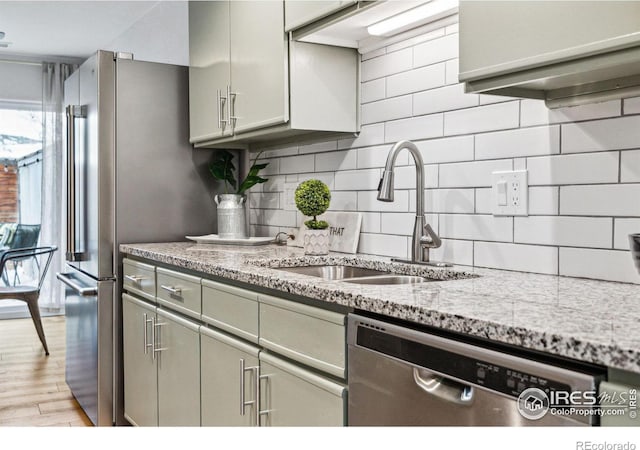 kitchen with sink, light hardwood / wood-style flooring, dishwasher, light stone countertops, and decorative backsplash