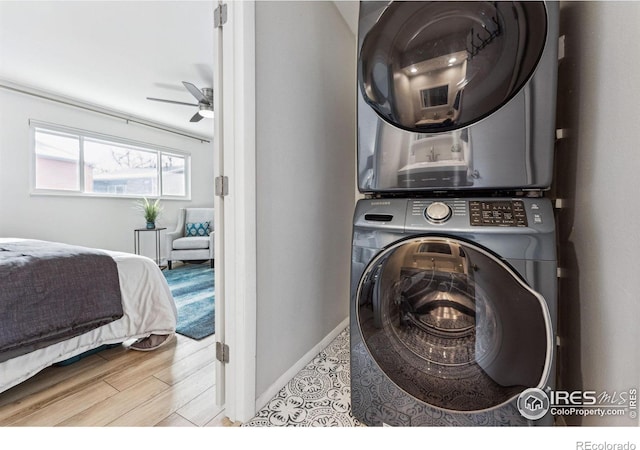 laundry area featuring stacked washer / dryer, ceiling fan, and light hardwood / wood-style flooring