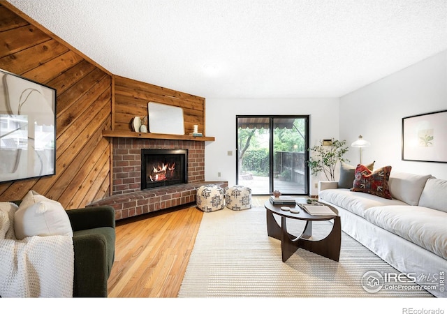 living room featuring a fireplace, wooden walls, and light hardwood / wood-style floors