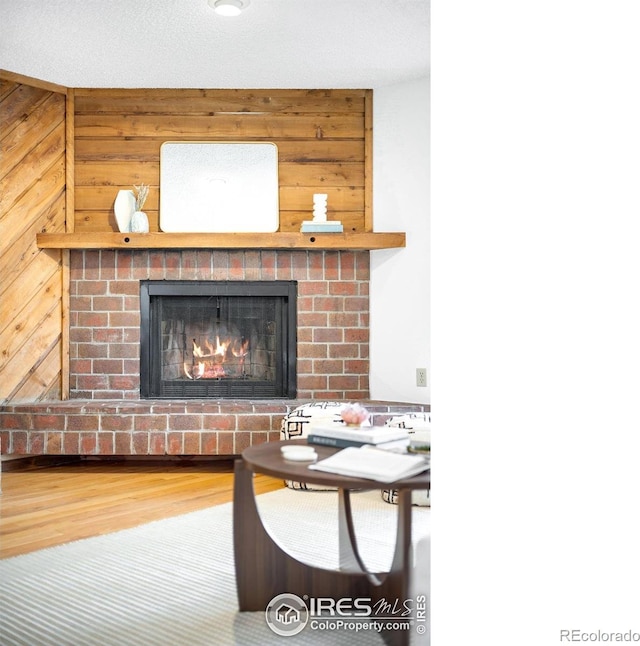 living room featuring wood-type flooring, a fireplace, and wood walls