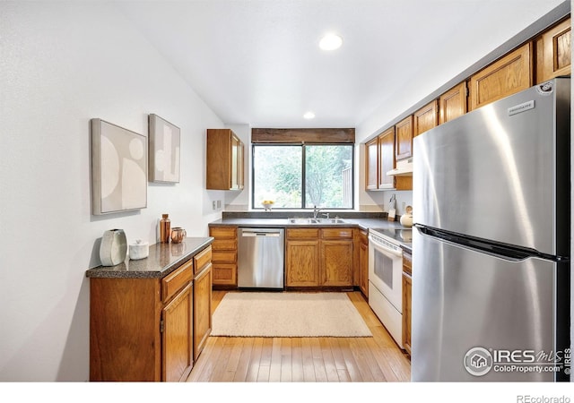 kitchen with stainless steel appliances, sink, and light hardwood / wood-style flooring