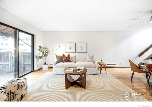 living room featuring ceiling fan, hardwood / wood-style floors, a textured ceiling, and baseboard heating