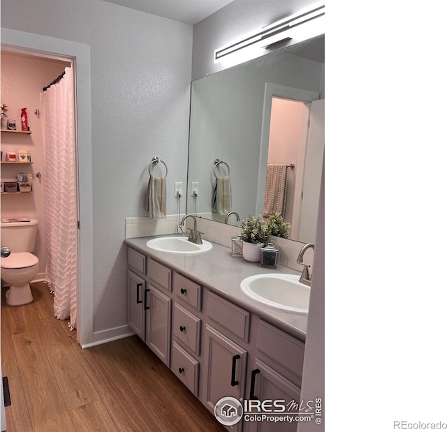 bathroom featuring wood-type flooring, vanity, and toilet