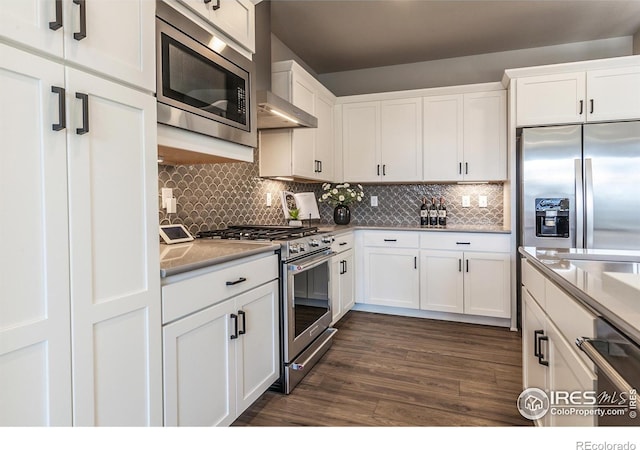 kitchen with stainless steel appliances, dark wood-type flooring, white cabinets, and backsplash