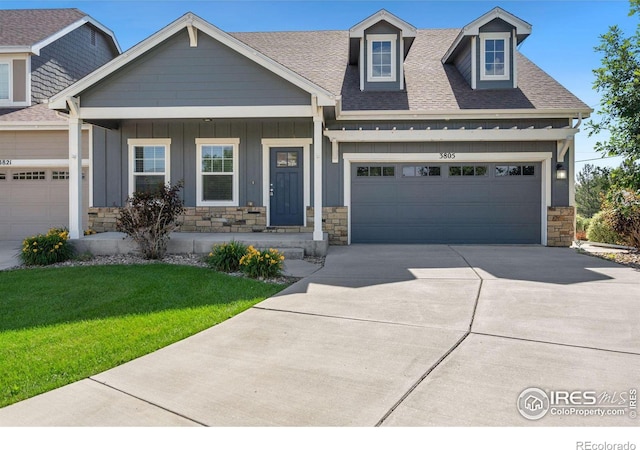 view of front of property featuring a porch, a garage, and a front lawn