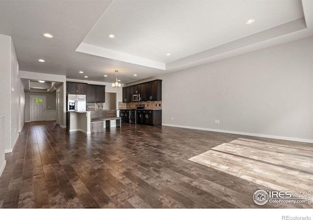 unfurnished living room featuring dark hardwood / wood-style floors and a raised ceiling