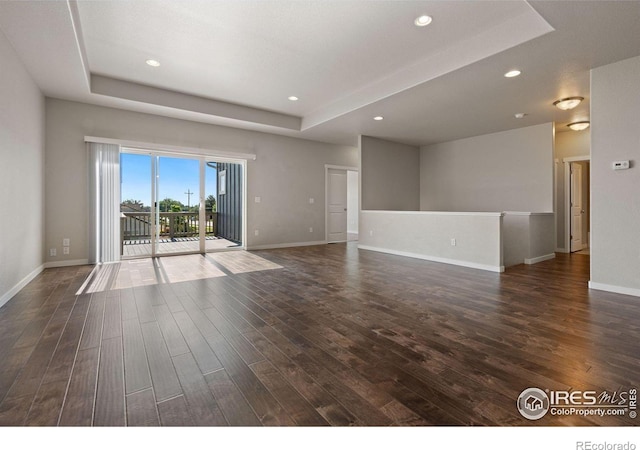 spare room with dark hardwood / wood-style flooring and a tray ceiling