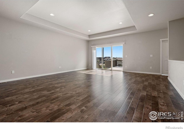 empty room featuring dark hardwood / wood-style floors and a raised ceiling