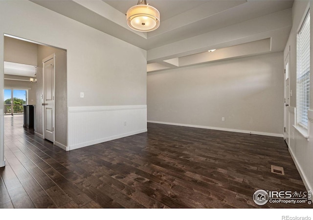 spare room with dark wood-type flooring and a tray ceiling