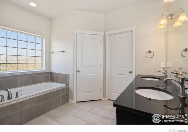 bathroom featuring a relaxing tiled tub, tile patterned floors, and vanity