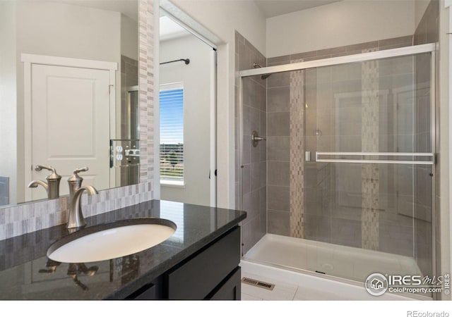 bathroom featuring vanity, an enclosed shower, and decorative backsplash