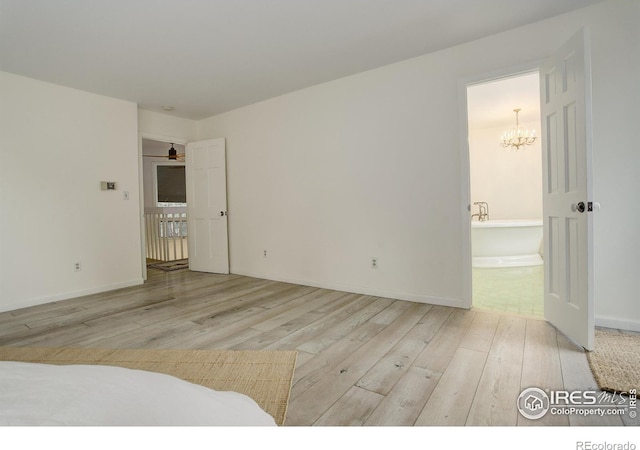 empty room with a chandelier and light hardwood / wood-style flooring