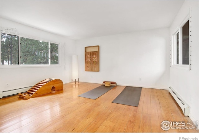 exercise room featuring a baseboard heating unit and wood-type flooring