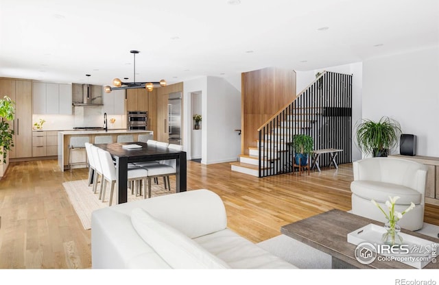 living room with sink, light hardwood / wood-style floors, and a chandelier